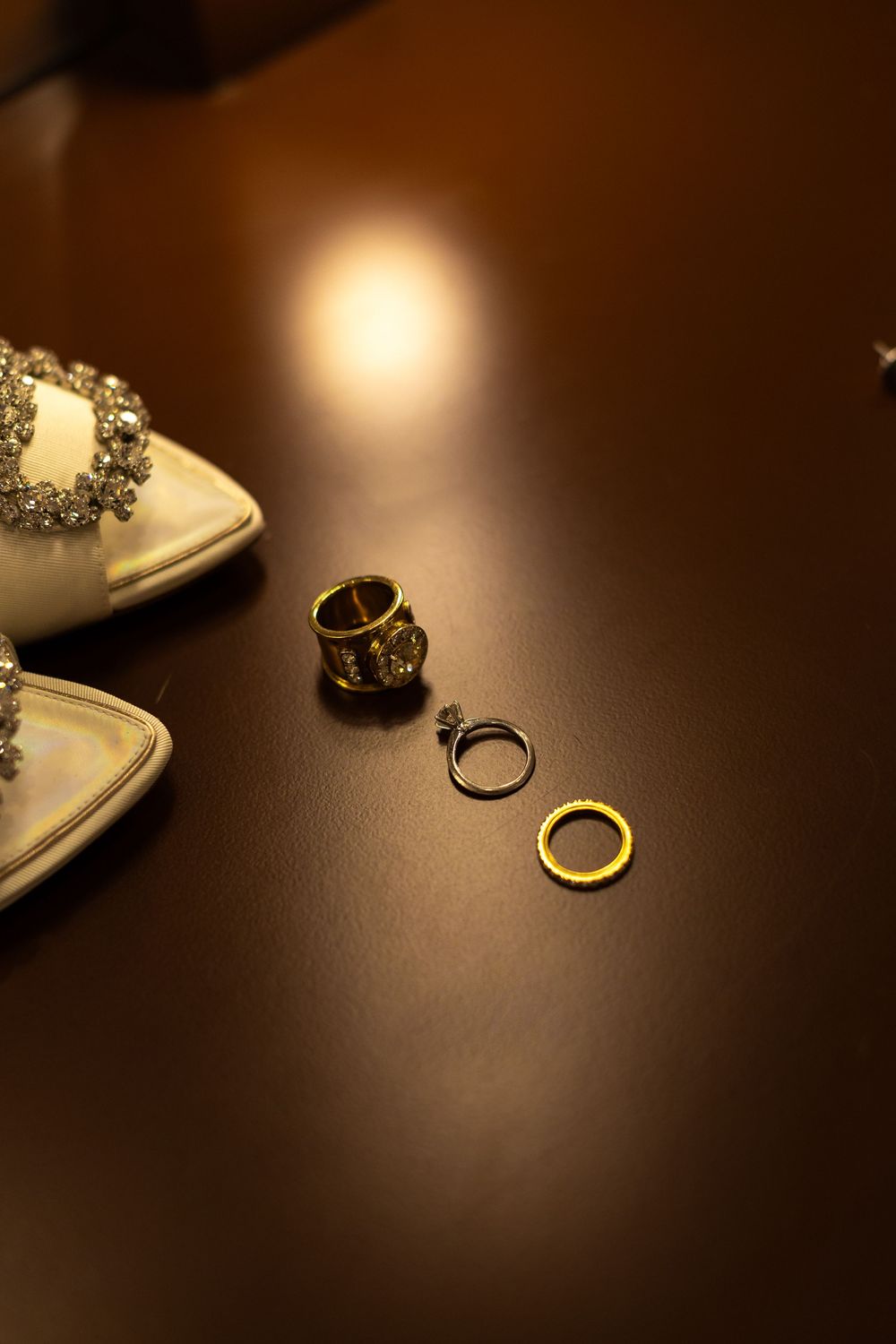 Wedding rings and jewelry arranged on a dark wooden surface with dramatic lighting.