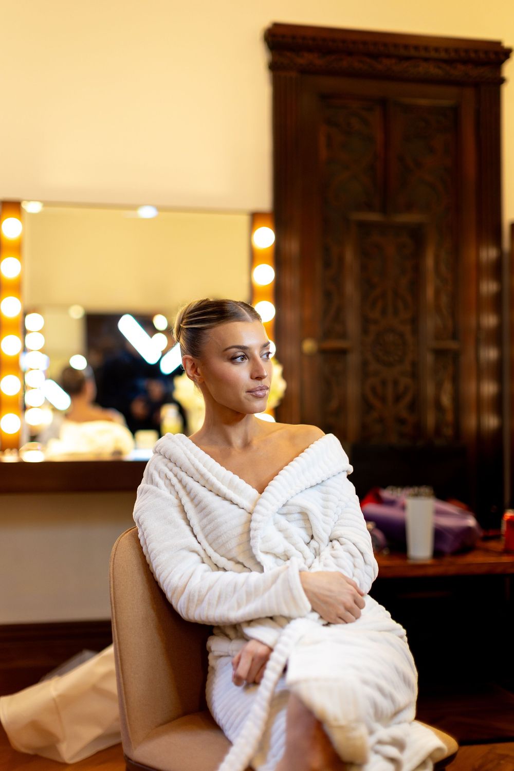 A person wearing a plush white robe relaxes in a warmly lit room.