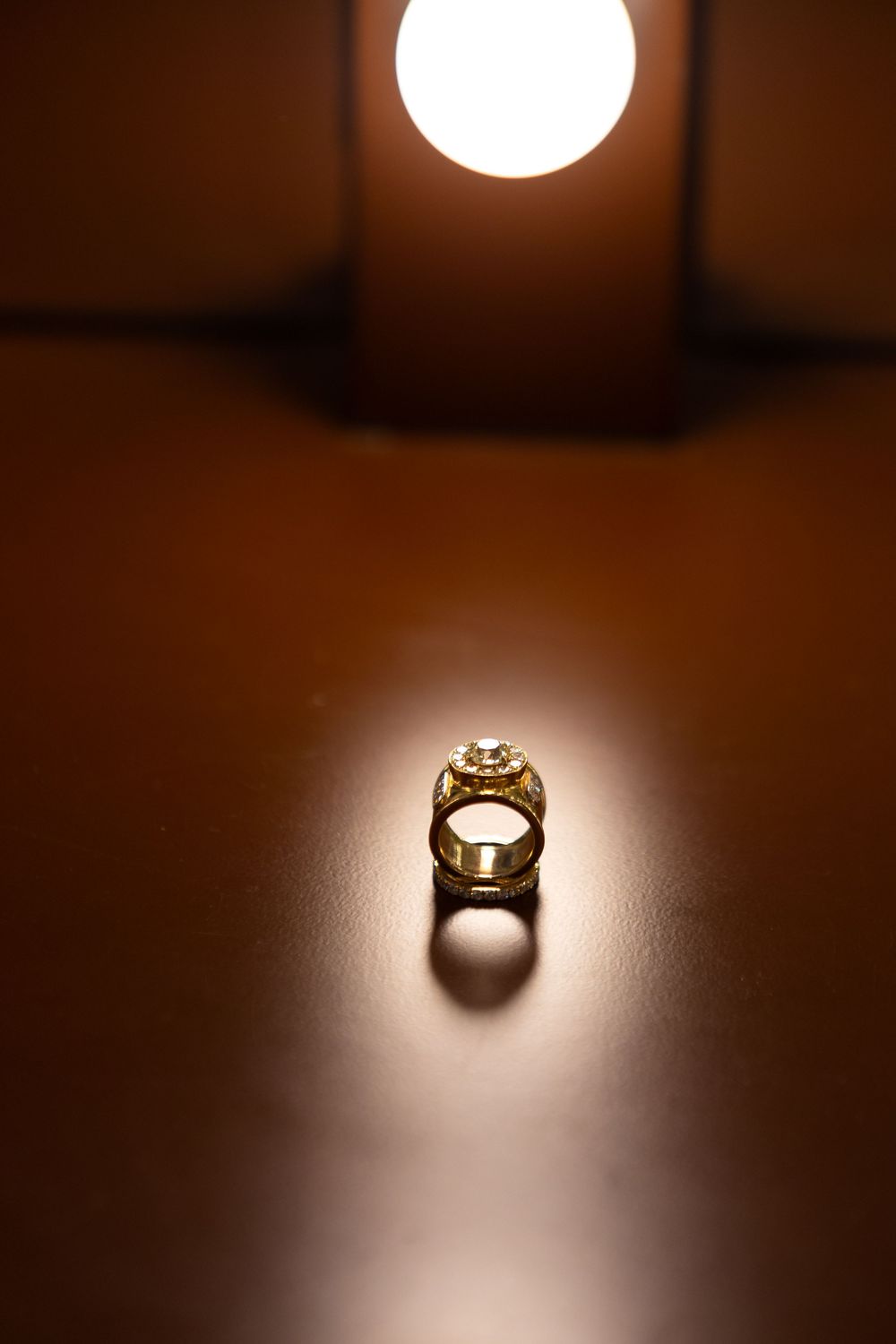 A dramatic sequence of photos showing a ring illuminated by a spotlight against a dark brown background.
