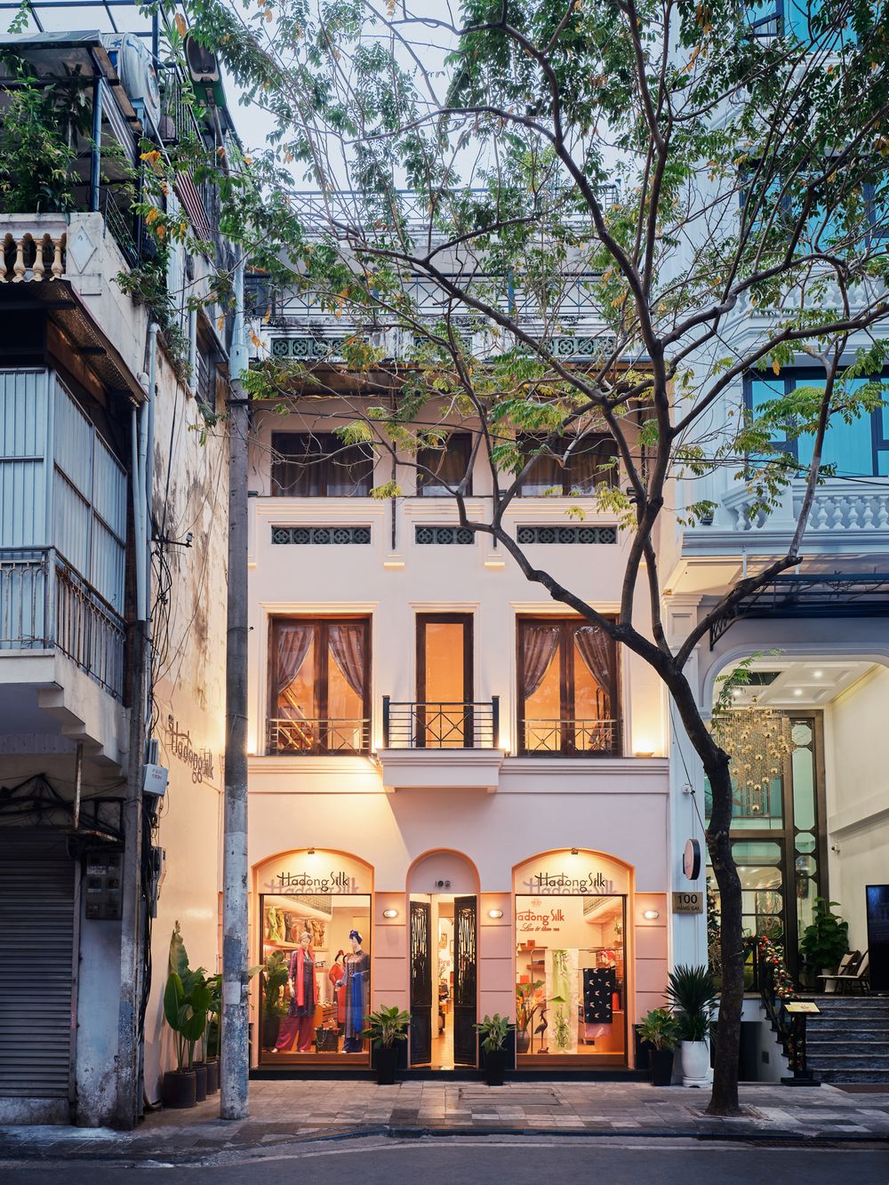 Facade of historic silk shop in Hanoi, Vietnam with warm lighting and classic architecture — street-level exterior by Khoi Ly.