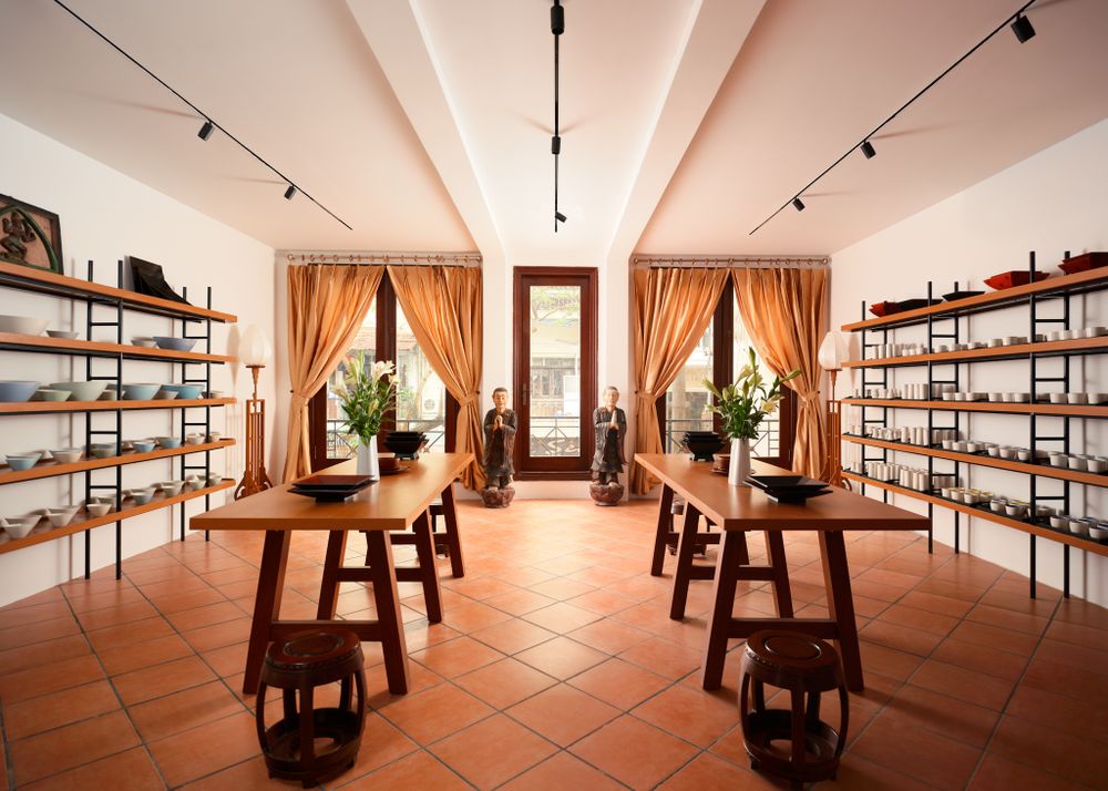 Artisan silk boutique with terracotta floors, symmetrical shelving, and traditional decor — photographed by Khoi Ly in Hanoi.