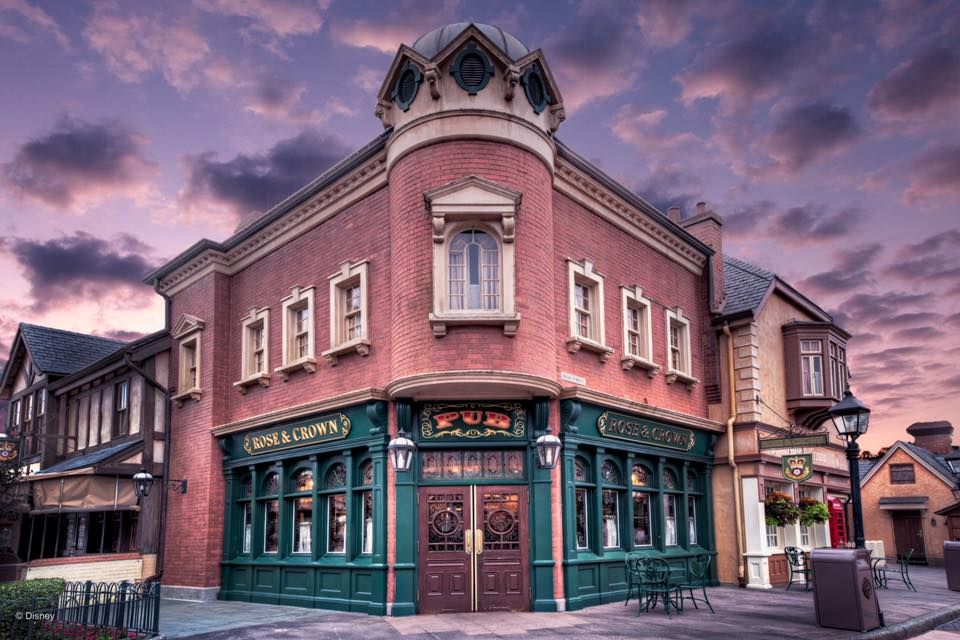 A pink Victorian-style corner building photographed at sunset with dramatic purple sky.