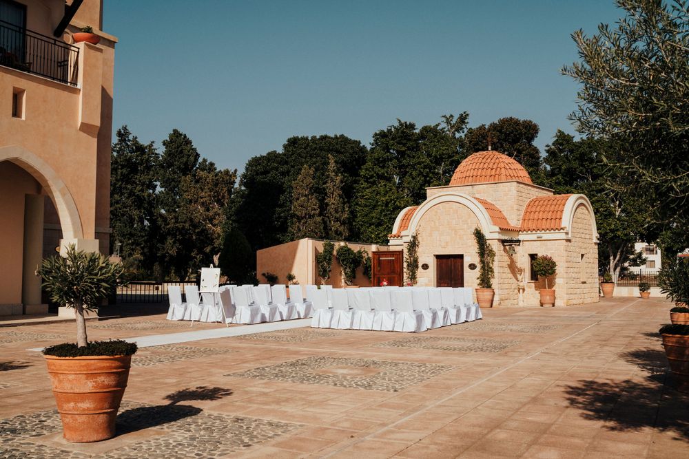 An outdoor wedding venue with Spanish architecture featuring terra cotta domes and white chair arrangements.