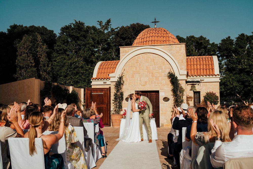 A wedding celebration at a Mediterranean-style venue with guests gathered around an ornate domed archway.