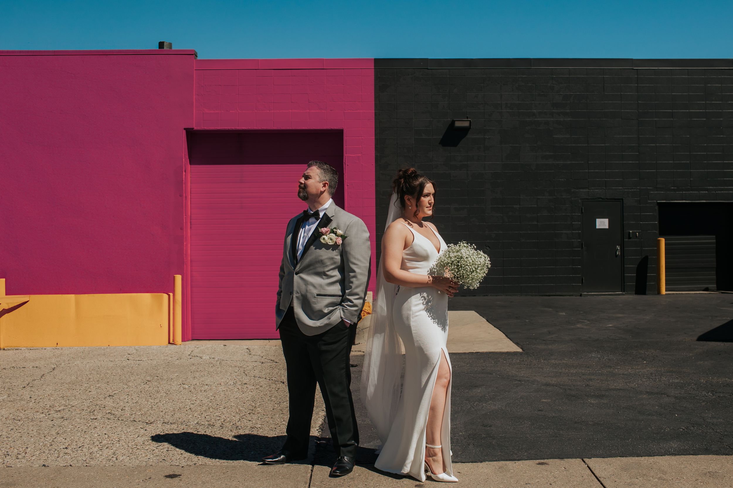A couple in wedding attire poses against colorful walls during a modern urban photoshoot in Indianapolis Indiana.
