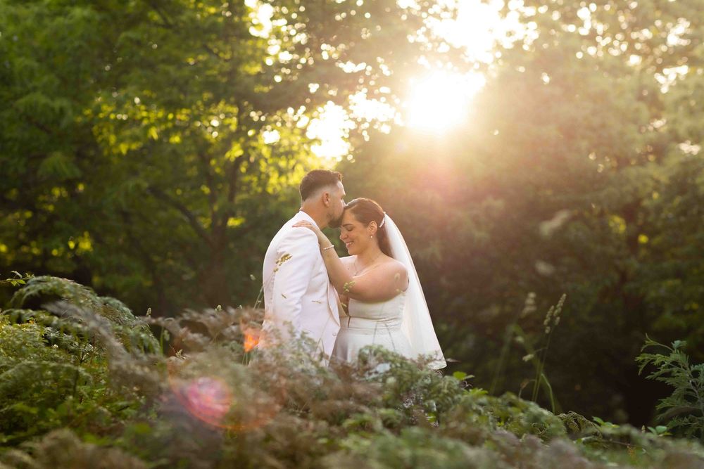 A couple shares an intimate moment in a sunlit garden during their outdoor photo session at golden hour.