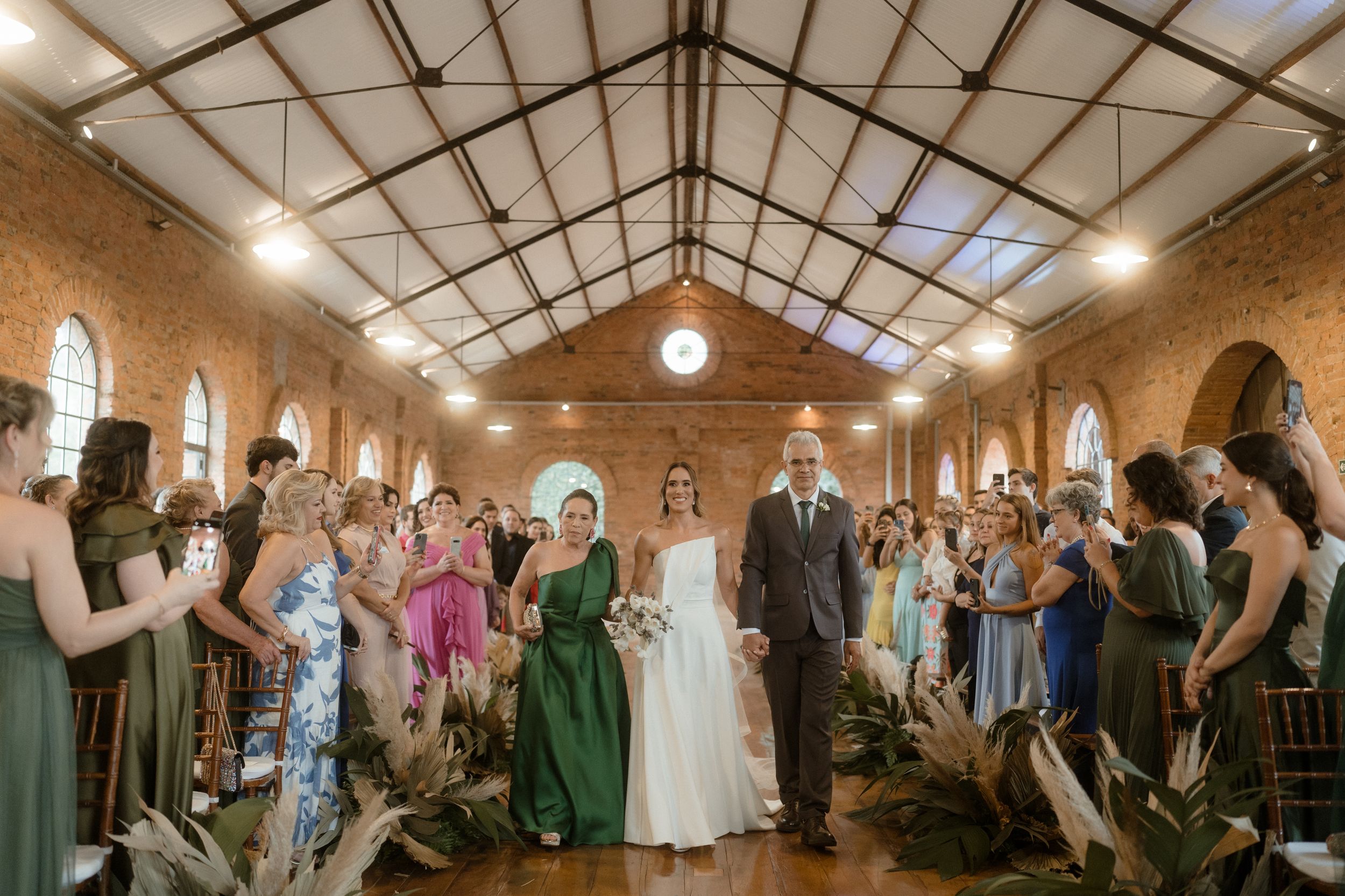Wedding ceremony in historic brick chapel with guests standing while couple exchanges vows at the altar.