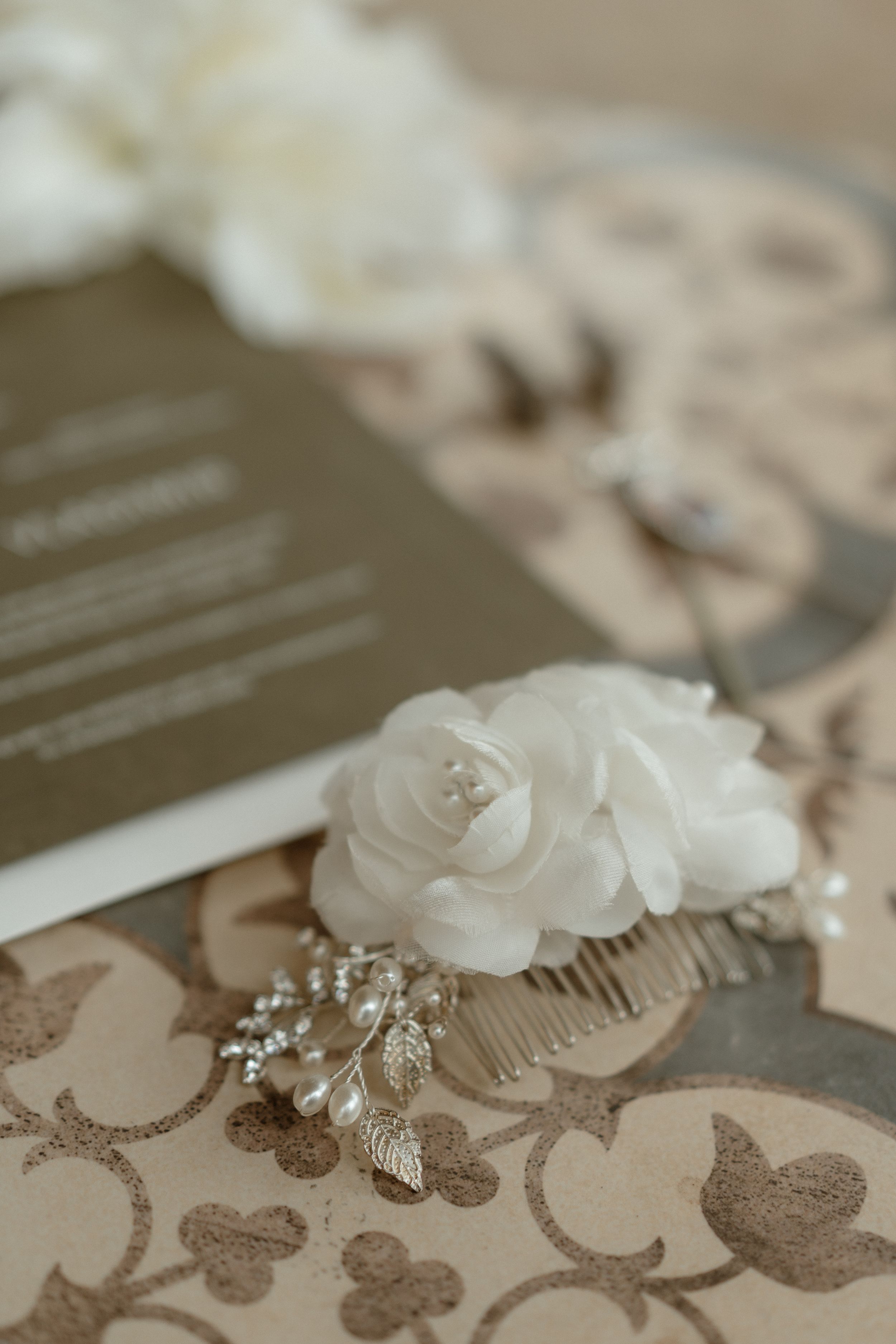 White floral hair accessories and jewelry arranged on patterned surface.