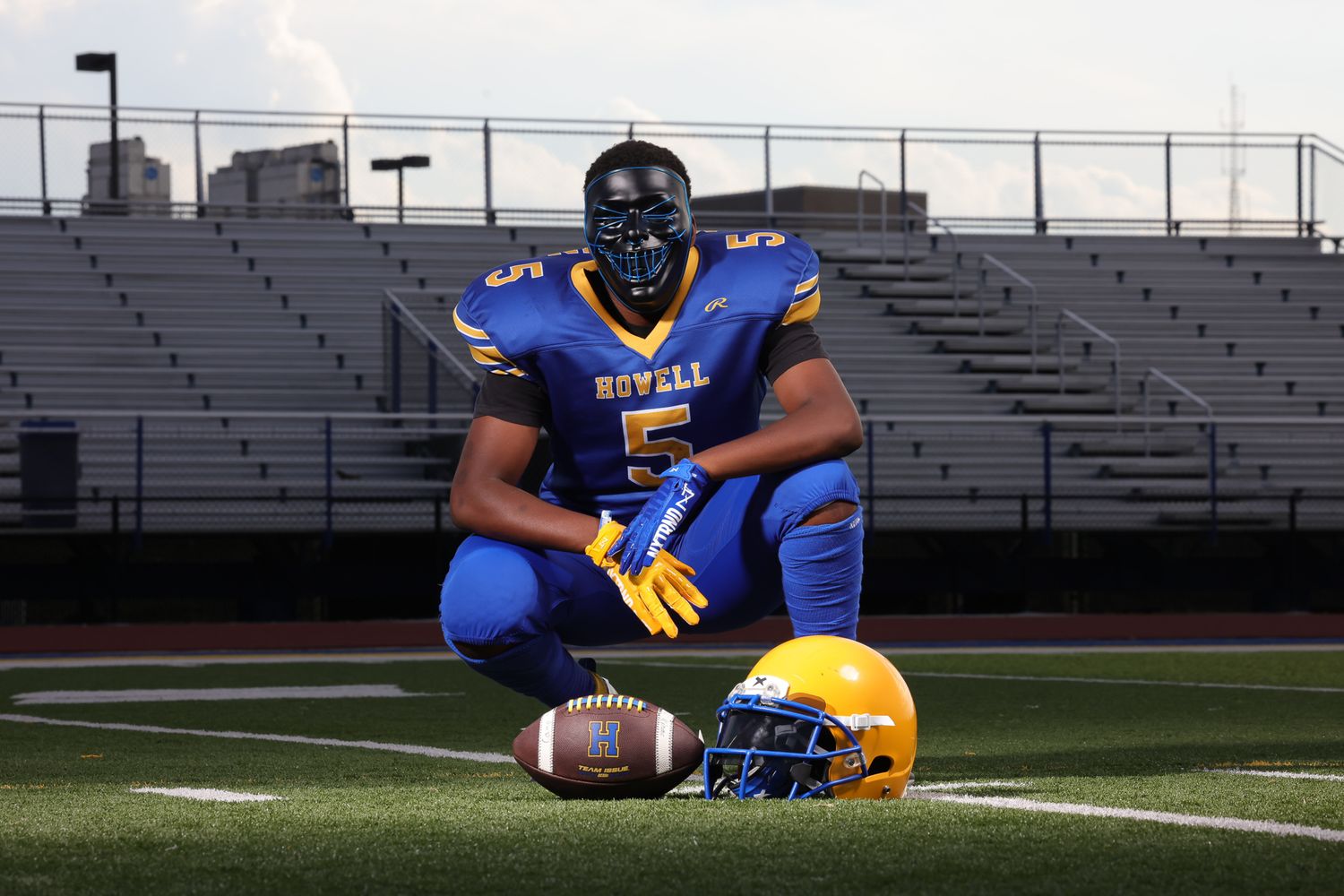 Football players in blue and gold uniforms pose on a field during a sports photo session.