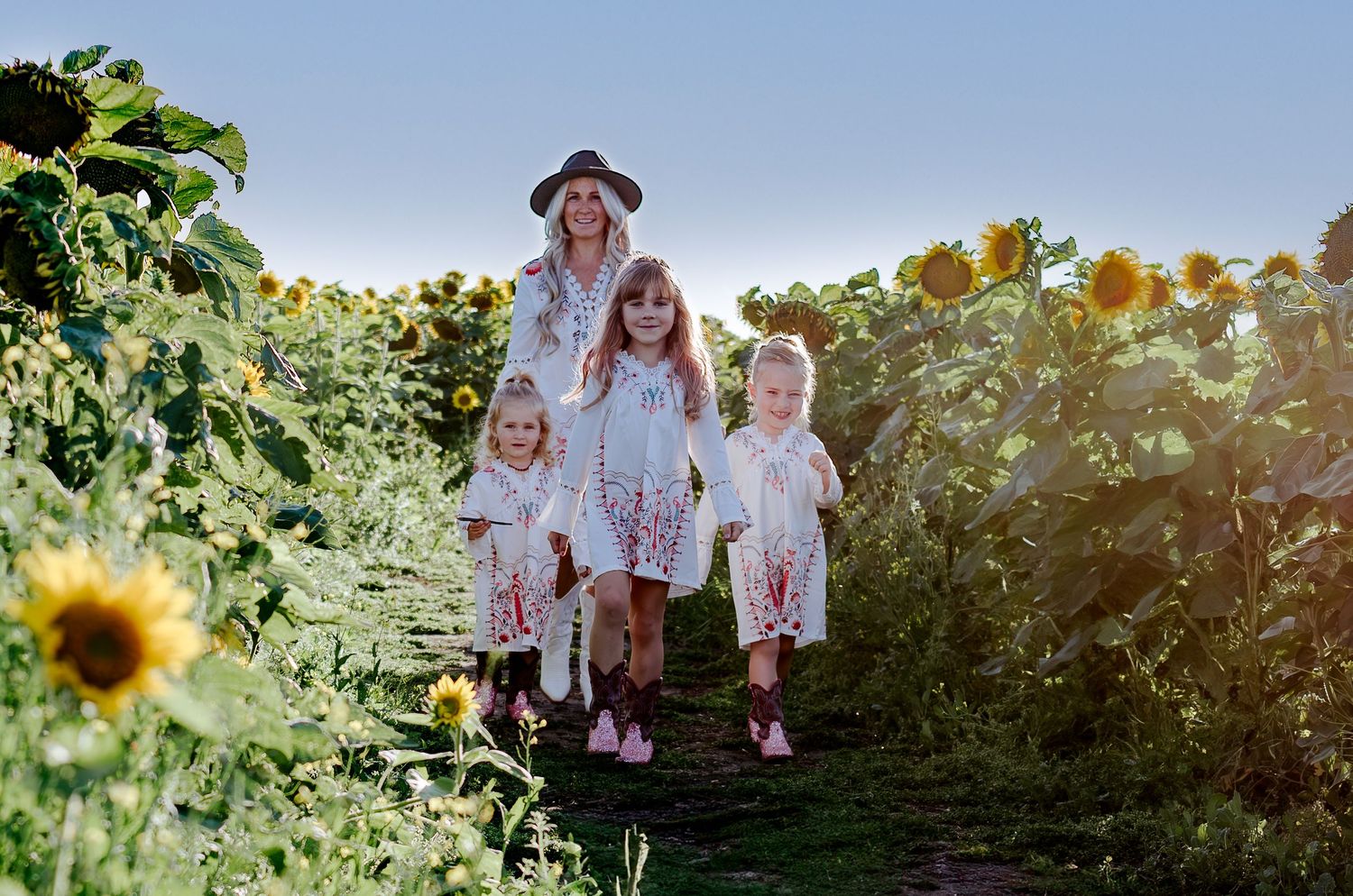 A family poses together in a blooming sunflower field during golden hour.