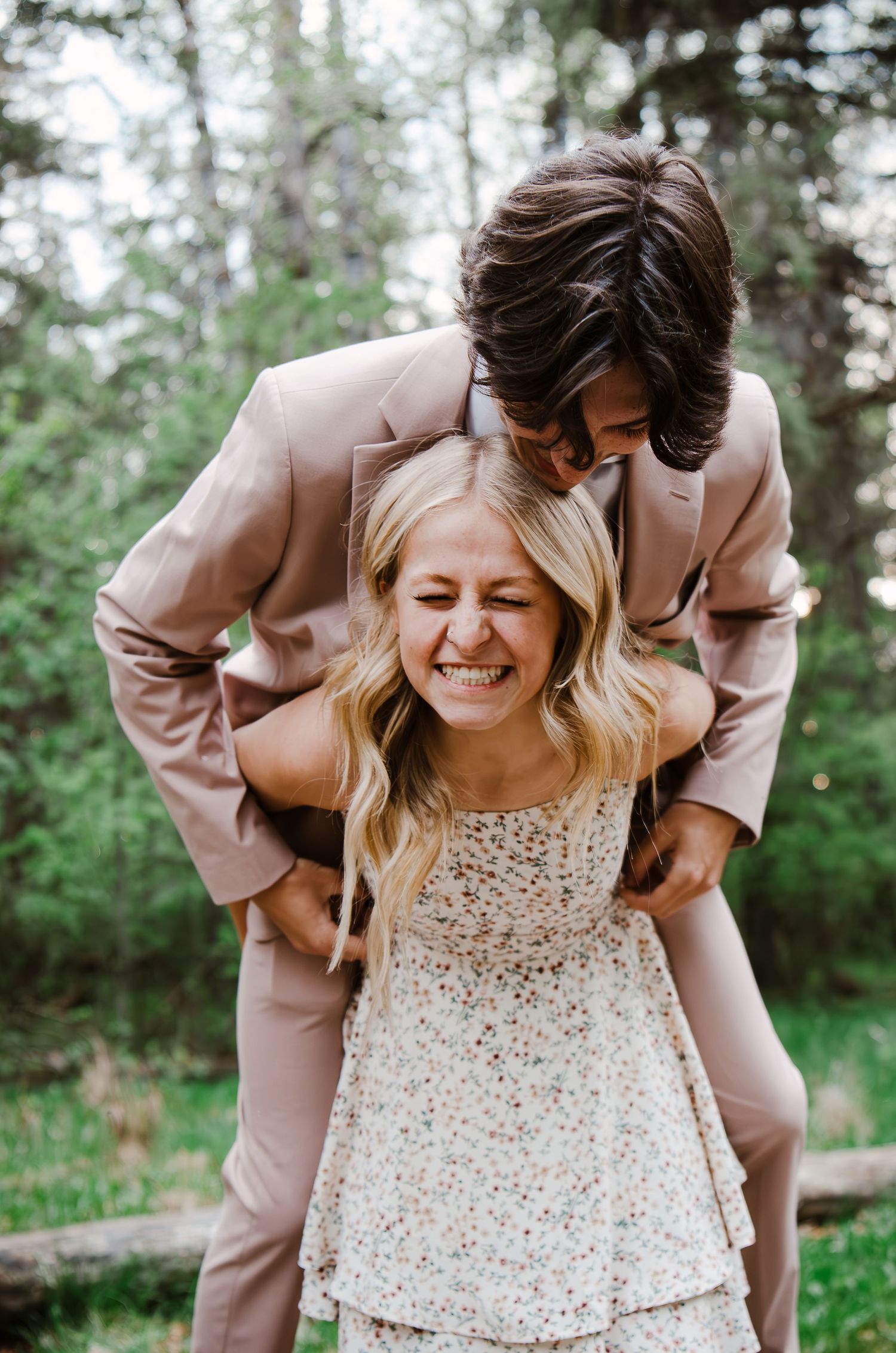 Couple sharing joyful moment in wooded setting wearing formal attire.