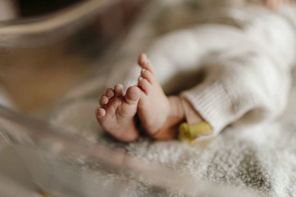 Close-up of tiny baby feet and toes against soft white blanket.