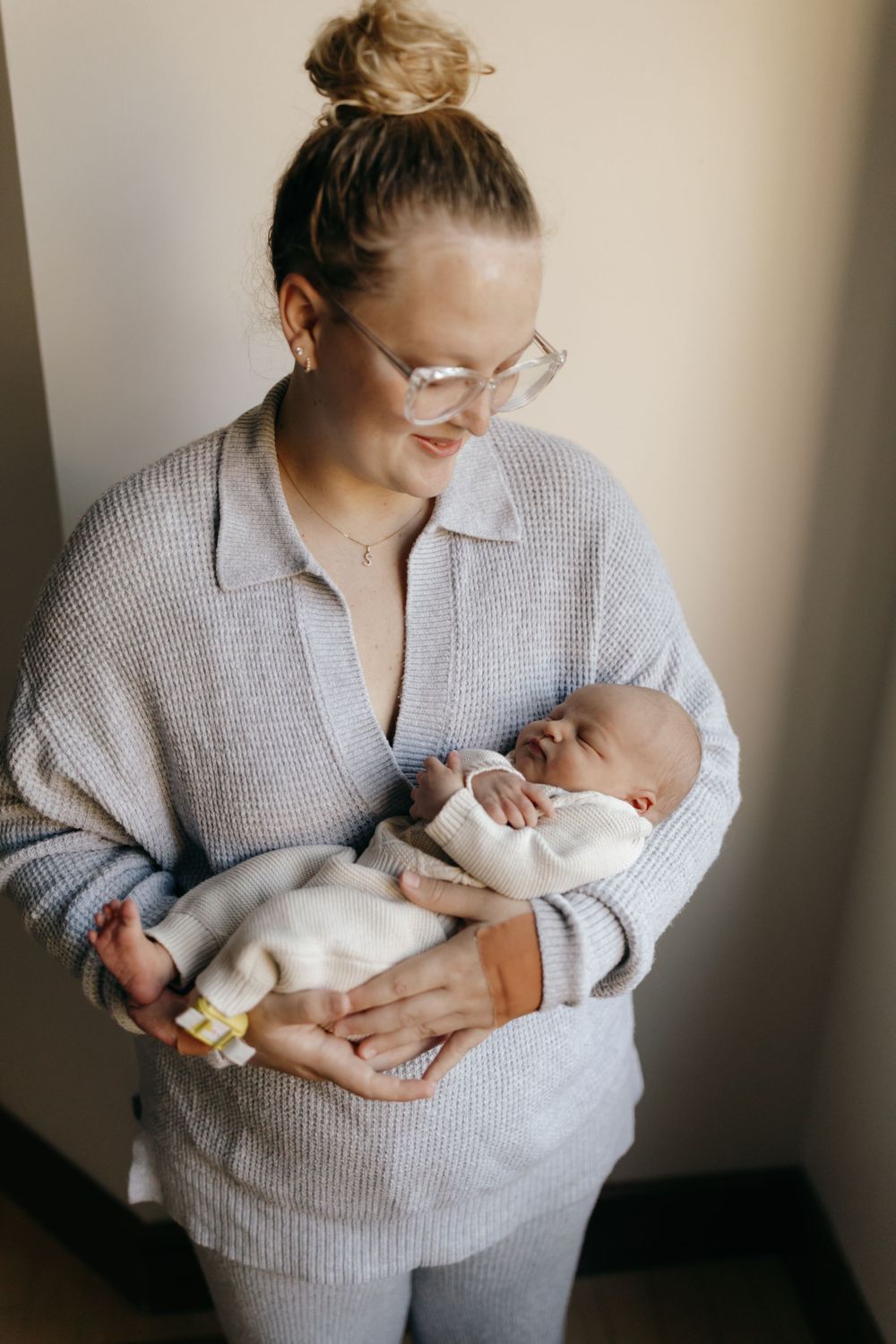 Gentle moment between caregiver in gray sweater and sleeping baby.