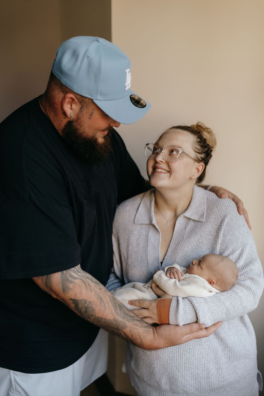 A couple shares an intimate moment with their newborn baby in a cozy indoor setting.
