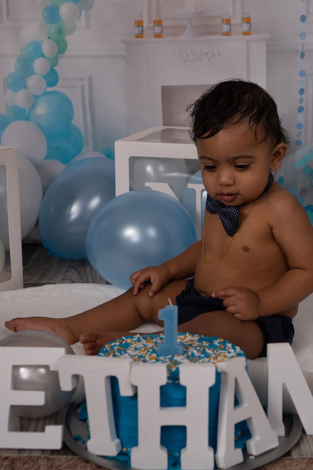 First birthday celebration setup with blue and white balloons and cake.