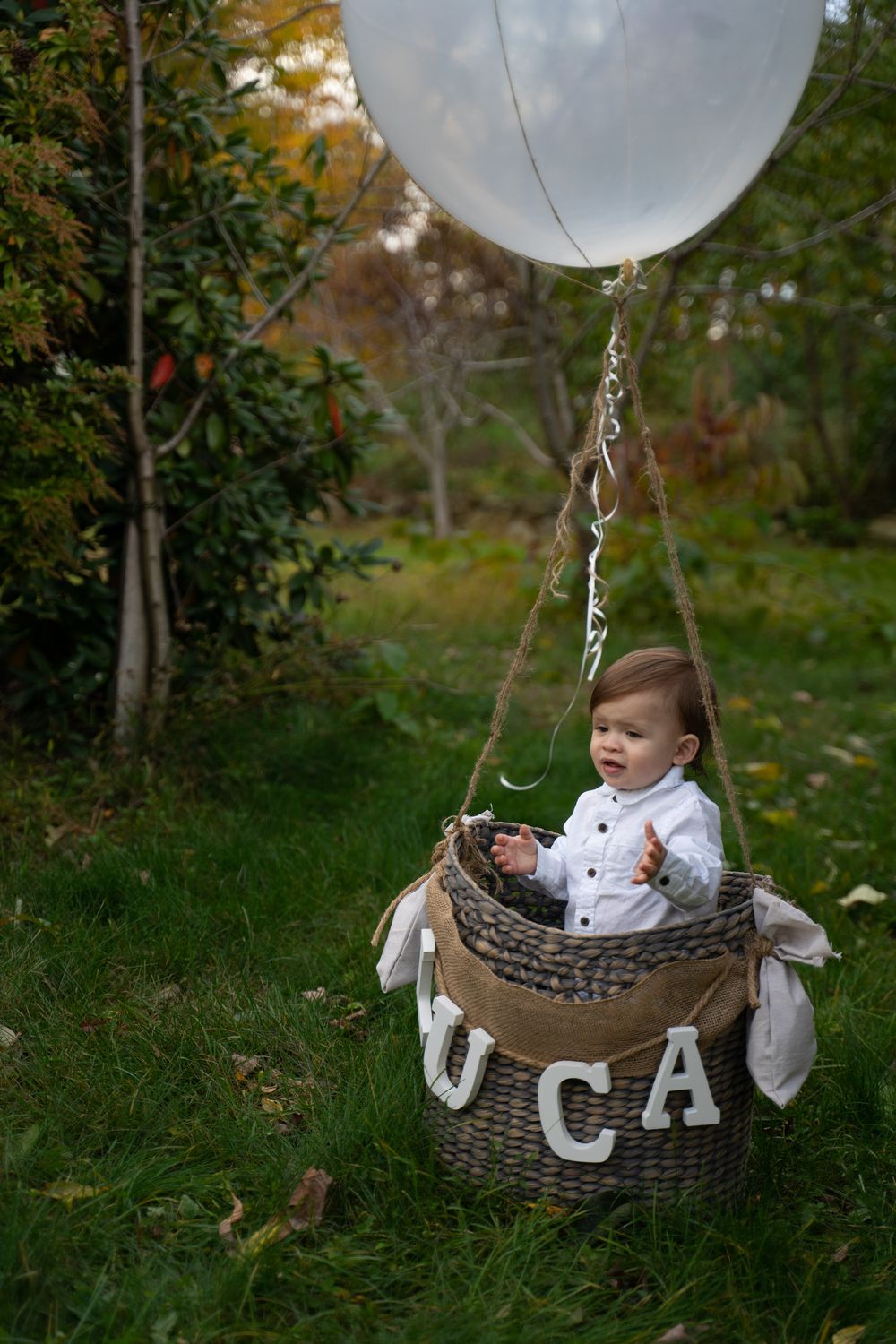 Woven basket with white balloon attached in autumn outdoor setting.