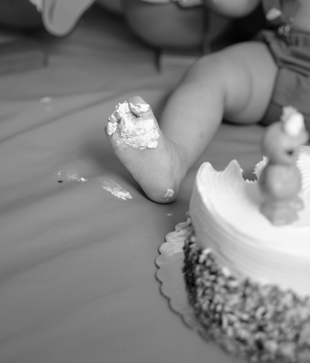 A close-up black and white photo of a decorated cake with a frosted finger swiping across the top.