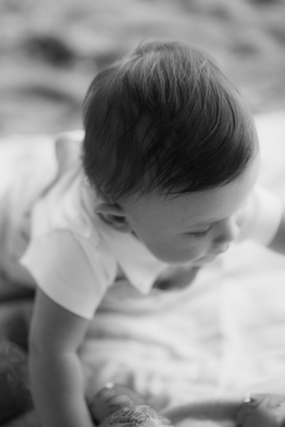 Black and white close-up of baby looking down in soft focus.