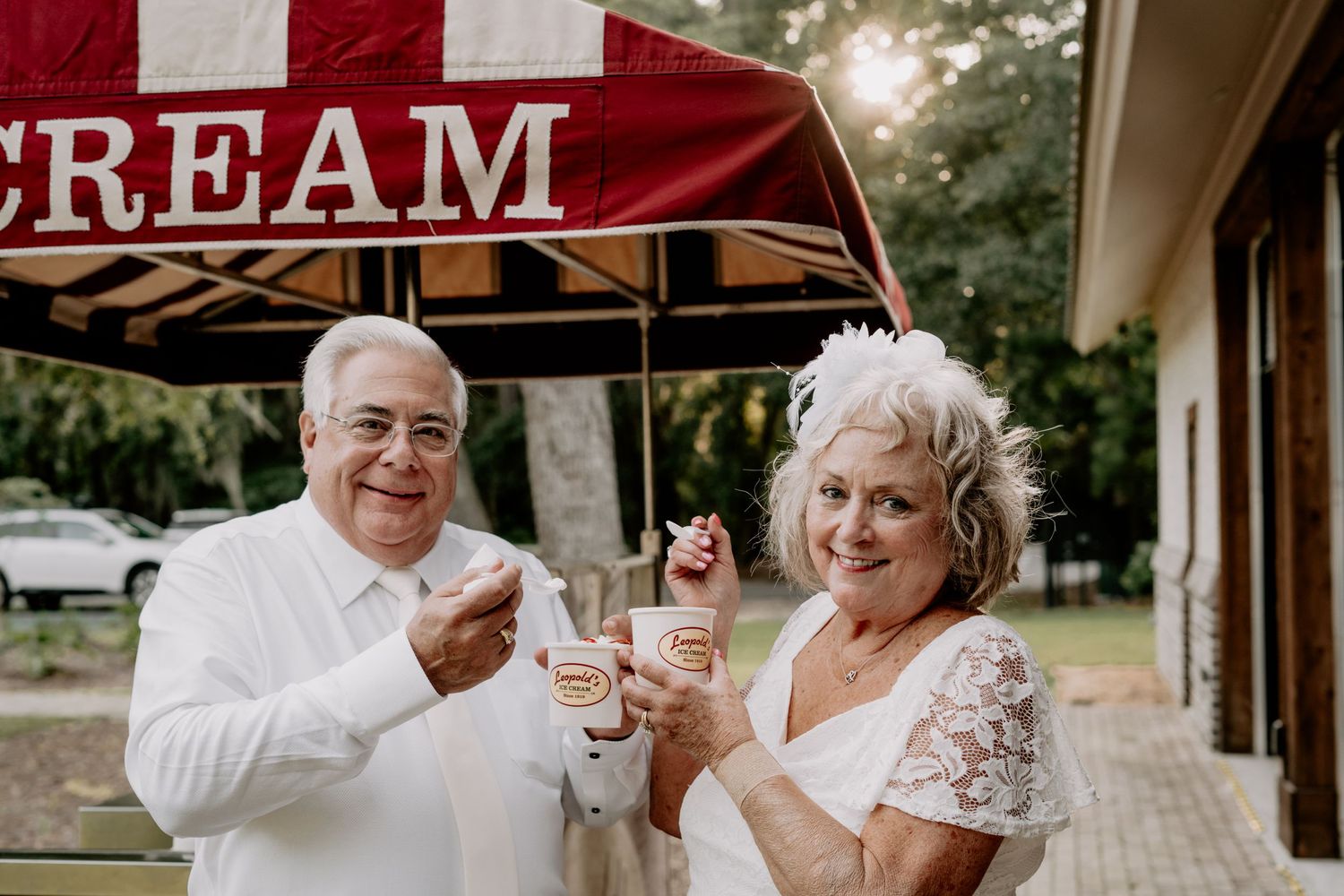 A couple enjoys ice cream together under a red awning on a summer day.