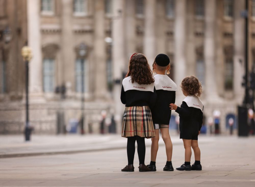 Picture of the backs of 3 children in the city of London.