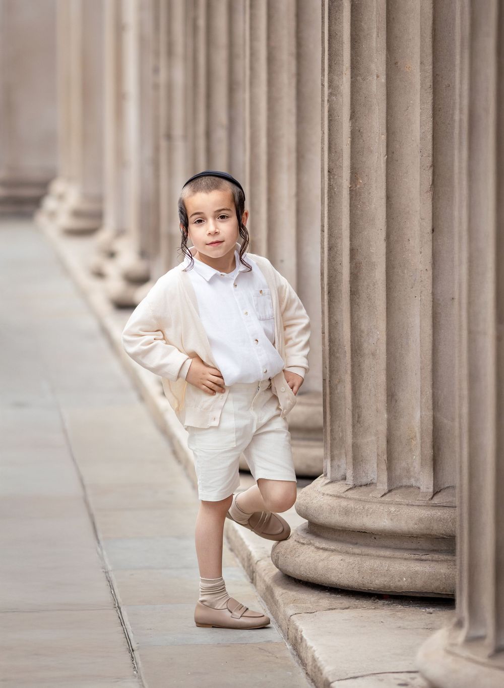 A boy leaning his leg on a  pillar.