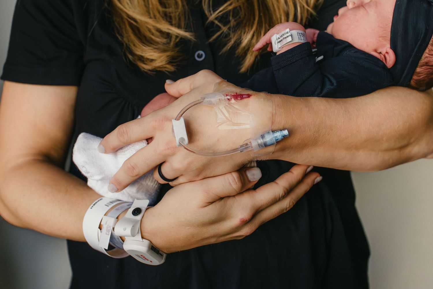 A baby receiving a medical vaccine injection while being held in supporting arms.