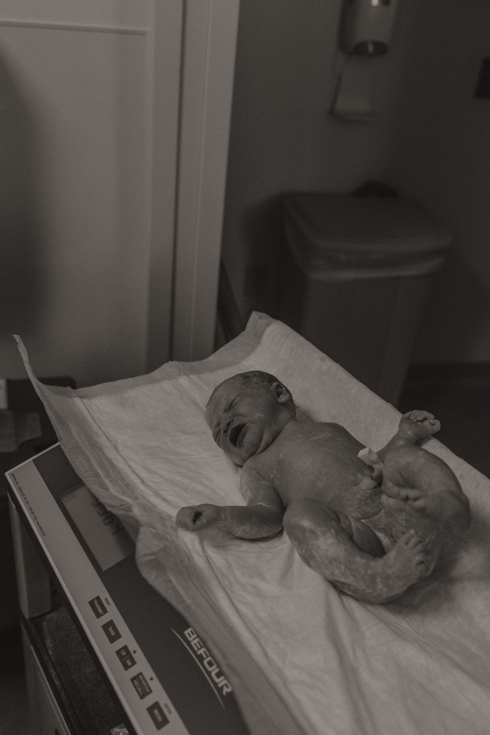 Series of black and white photos showing a newborn baby moments after birth on hospital bed.