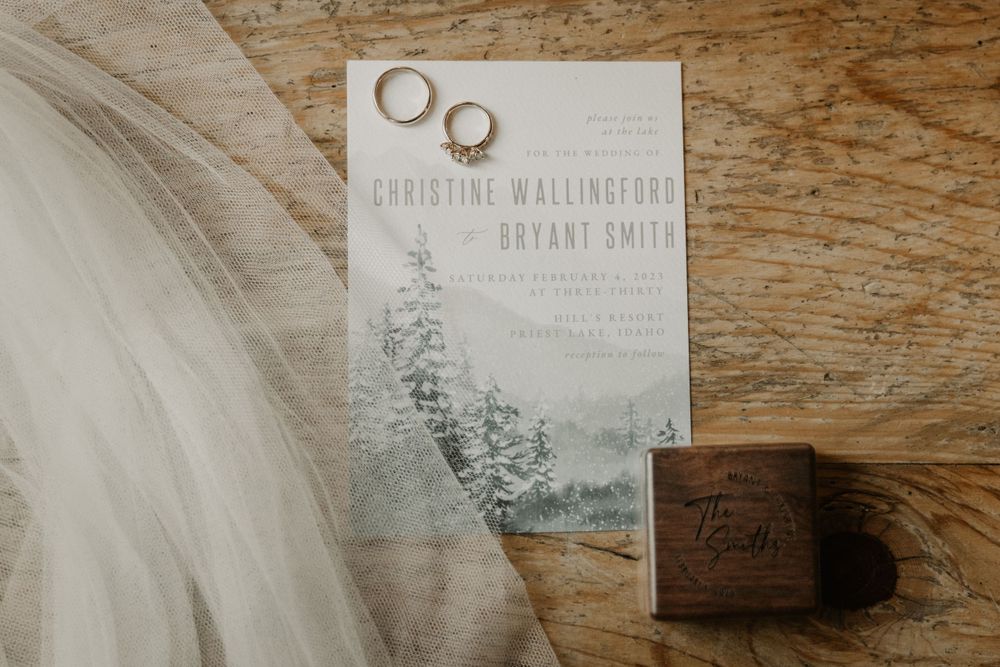 Wedding invitation and rings photographed on rustic wooden surface.