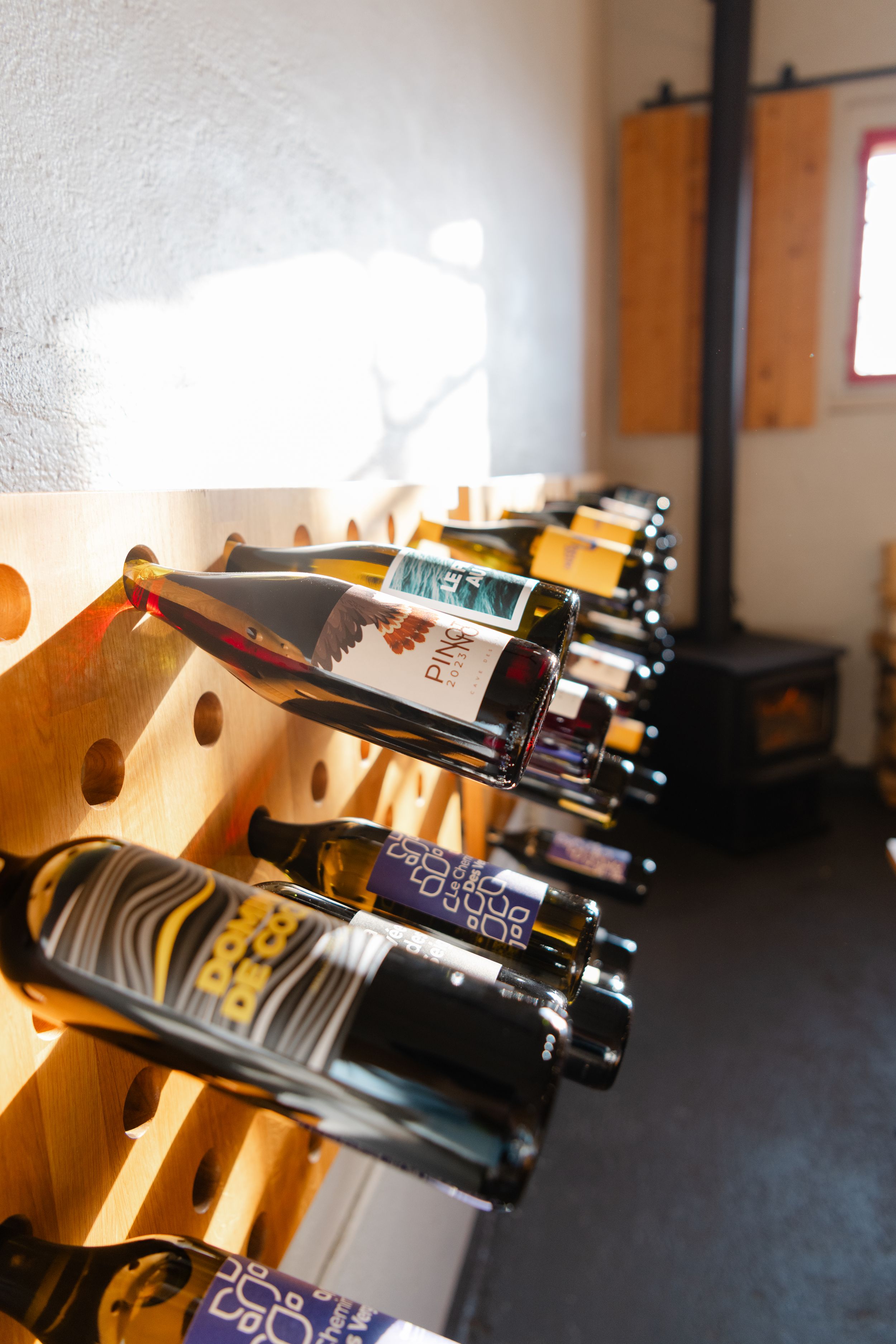 Row of wooden wine bottle holders displaying bottles at an angle in a dimly lit room.