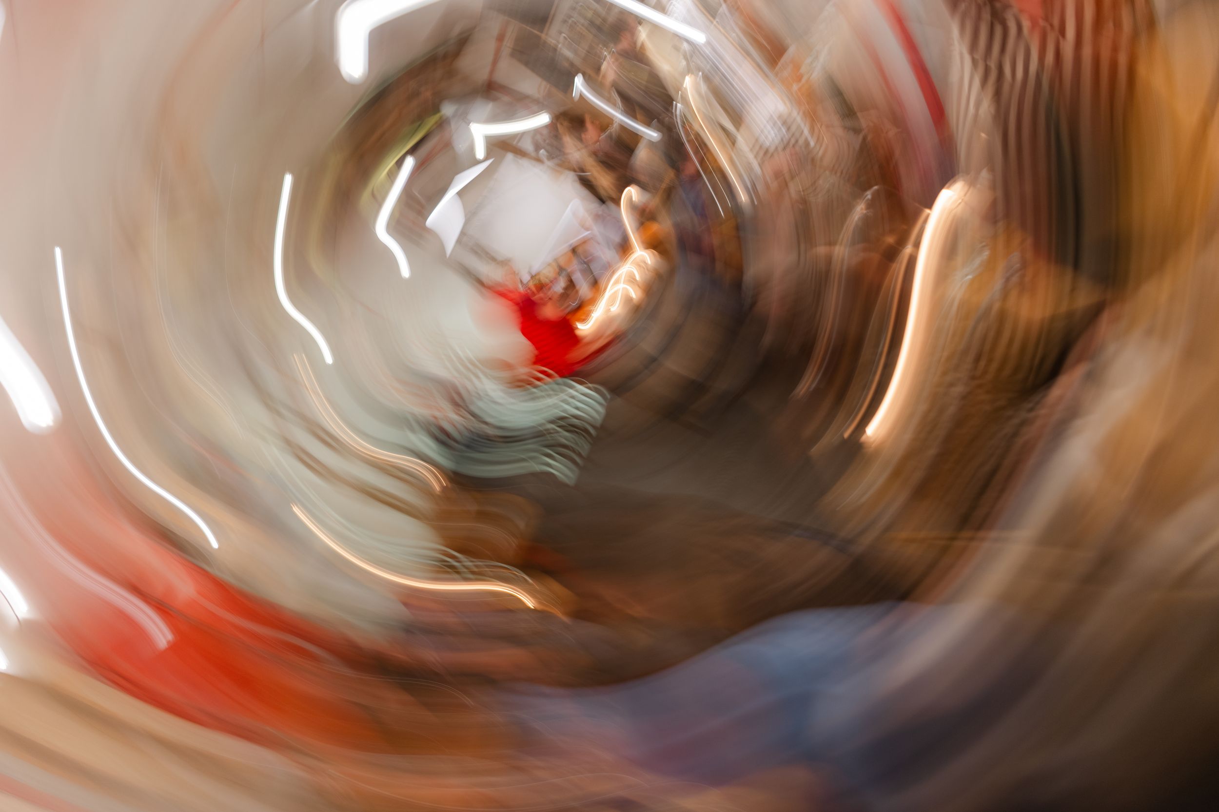 Abstract motion blur photograph with swirling brown and red tones creating a dynamic spiral pattern.