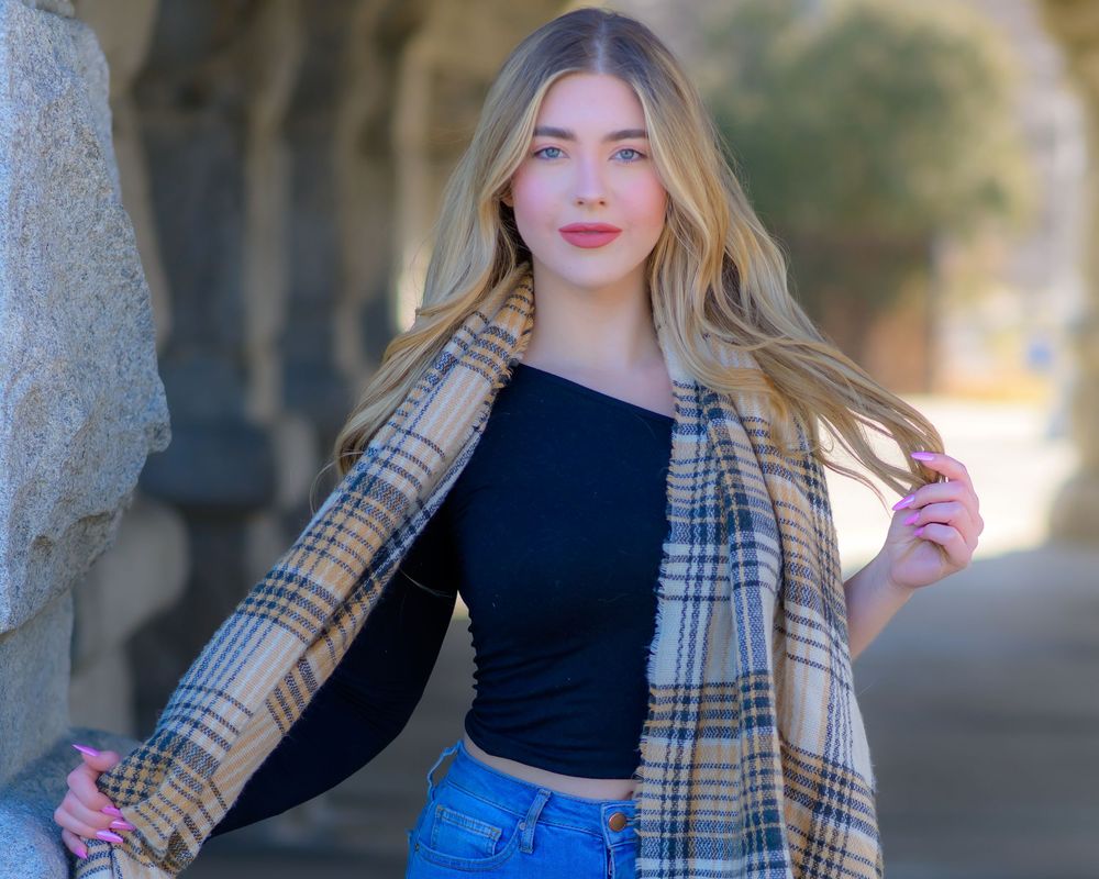 Fashion portrait series with plaid coat and blue jeans against stone architecture.