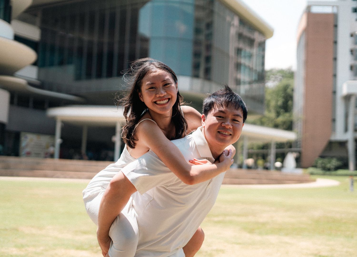 Cheerful piggyback moment captured on sunny campus grounds.