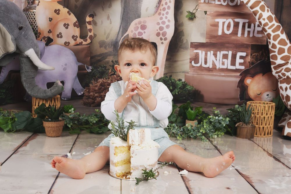 A first birthday cake smash photo session with pink and gold decorations in an outdoor garden setting.