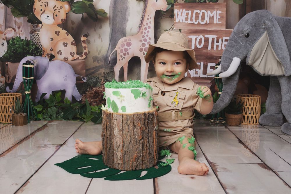 Whimsical woodland-themed photo setup with rustic tree stumps, welcome signs, and decorative elements on a gray floor.