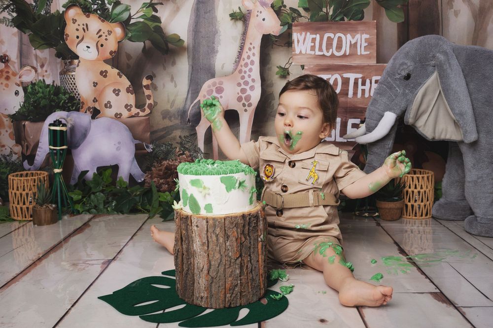 Enchanted forest photo backdrop with tree stumps, welcome signs, and green accents arranged on stone flooring.