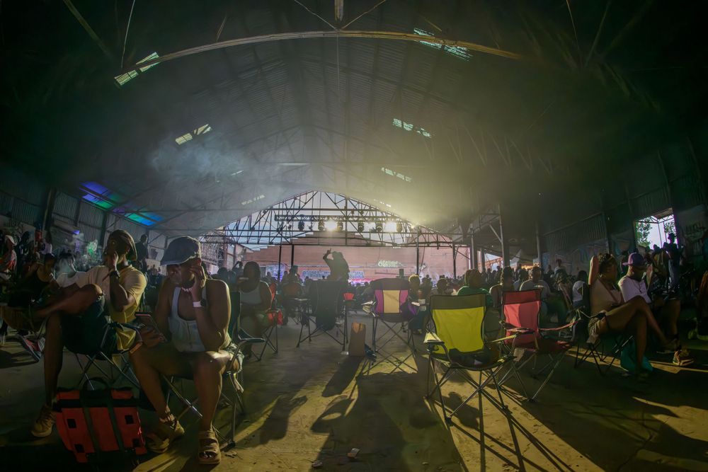 A crowded indoor concert venue with atmospheric lighting and silhouettes of people enjoying live music.
