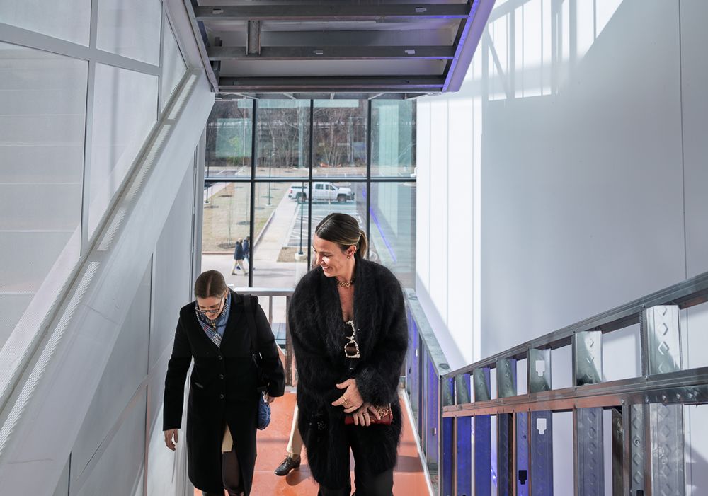 A couple shares a joyful moment in an elegant indoor venue with glass windows and modern architecture.