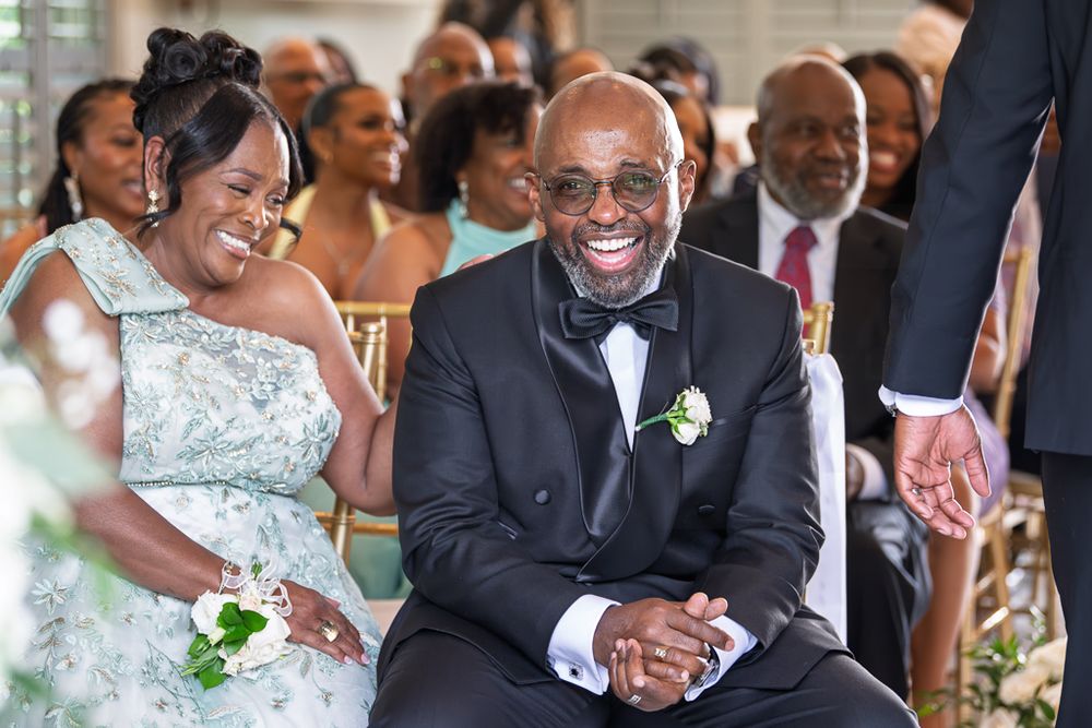 A couple shares laughter and smiles during their wedding celebration in a bright, elegant setting.