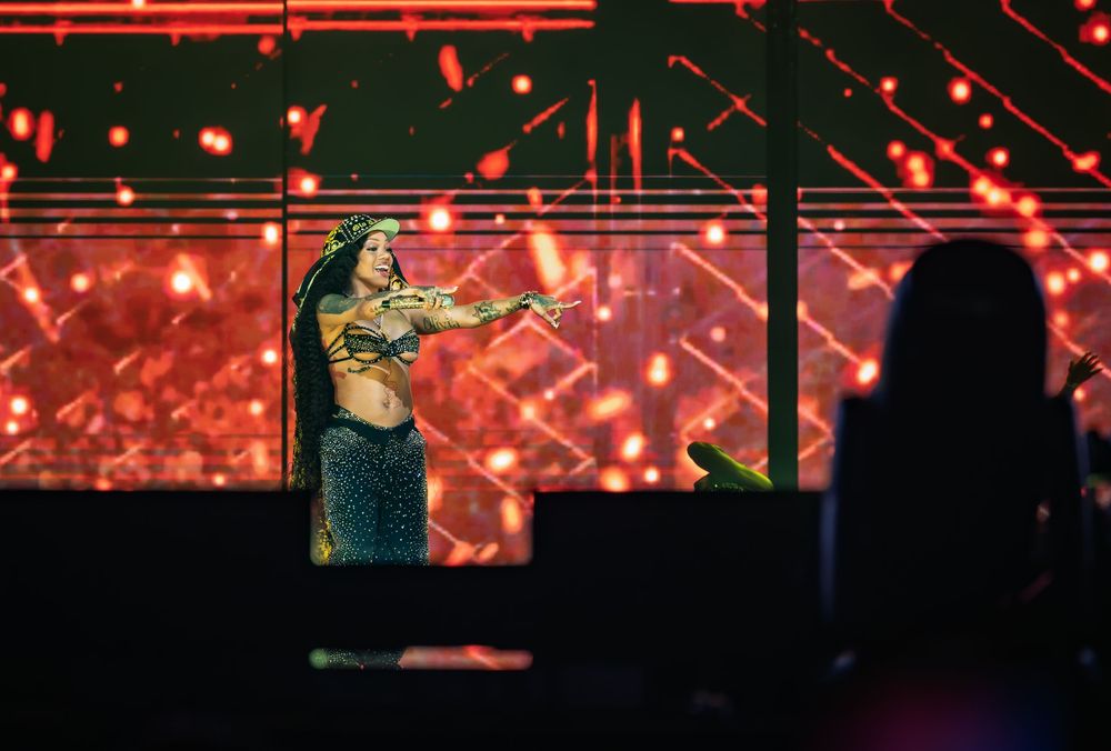 Concert performers on stage illuminated by vibrant red lighting and glowing effects during a live performance.