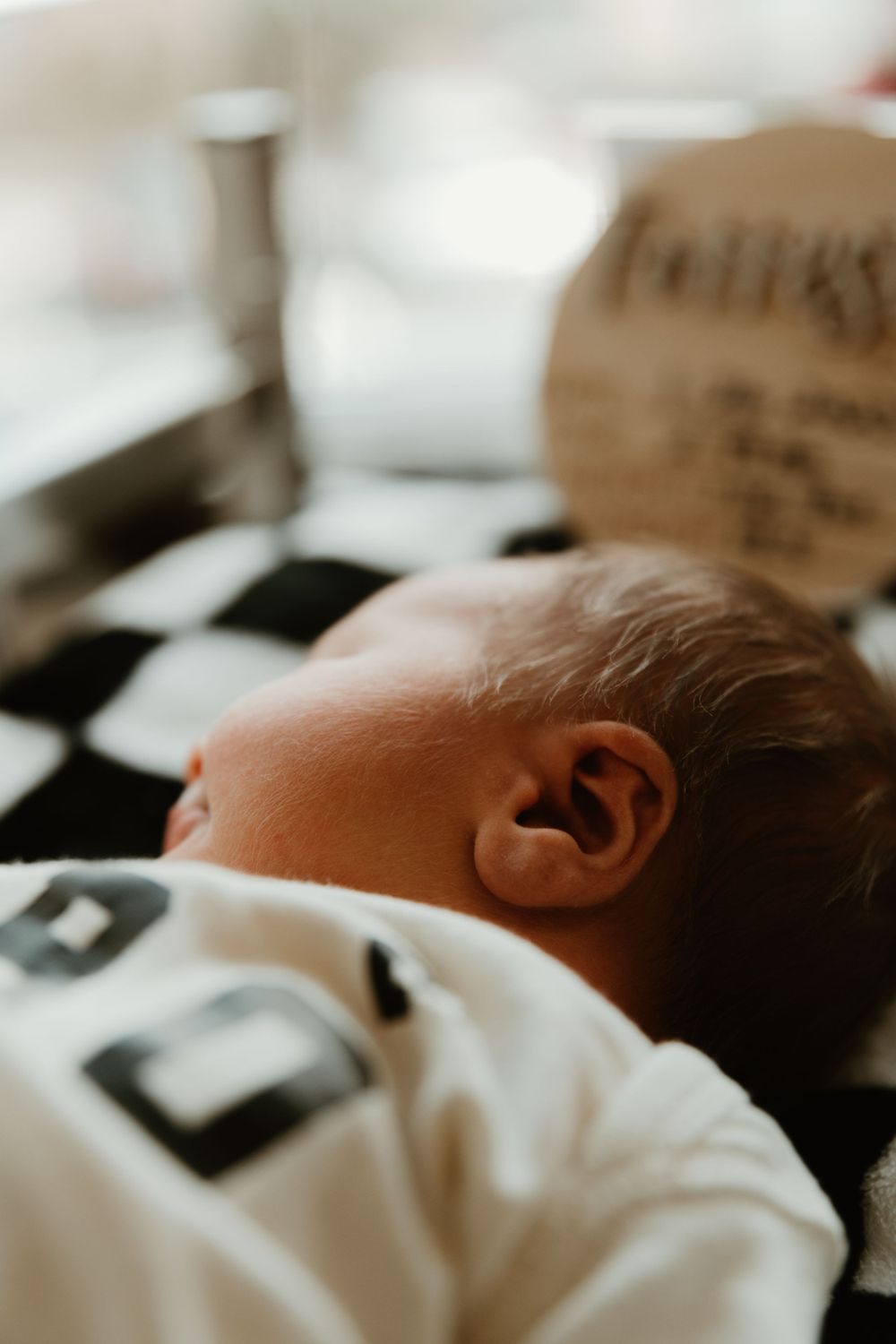 Close-up profile of sleeping newborn baby against checkered background.