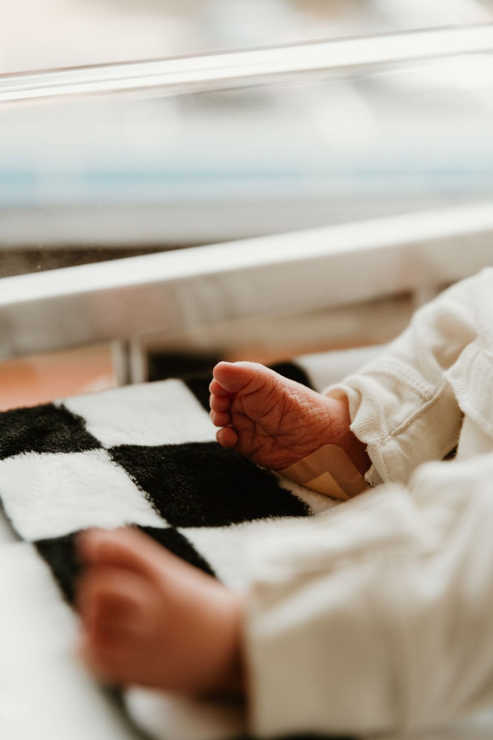 Sleeping newborn wearing a white onesie in a cozy indoor setting.
