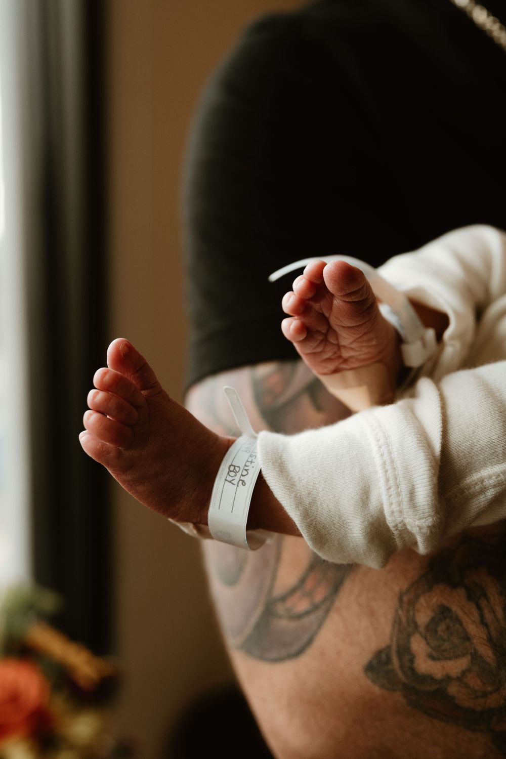 Small infant feet with hospital identification band in natural lighting.