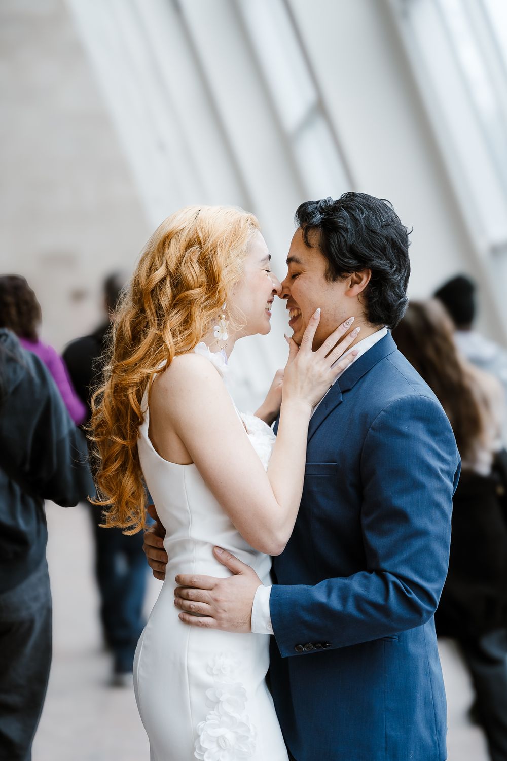 A romantic moment between newlyweds in formal attire sharing an intimate embrace by a bright window.