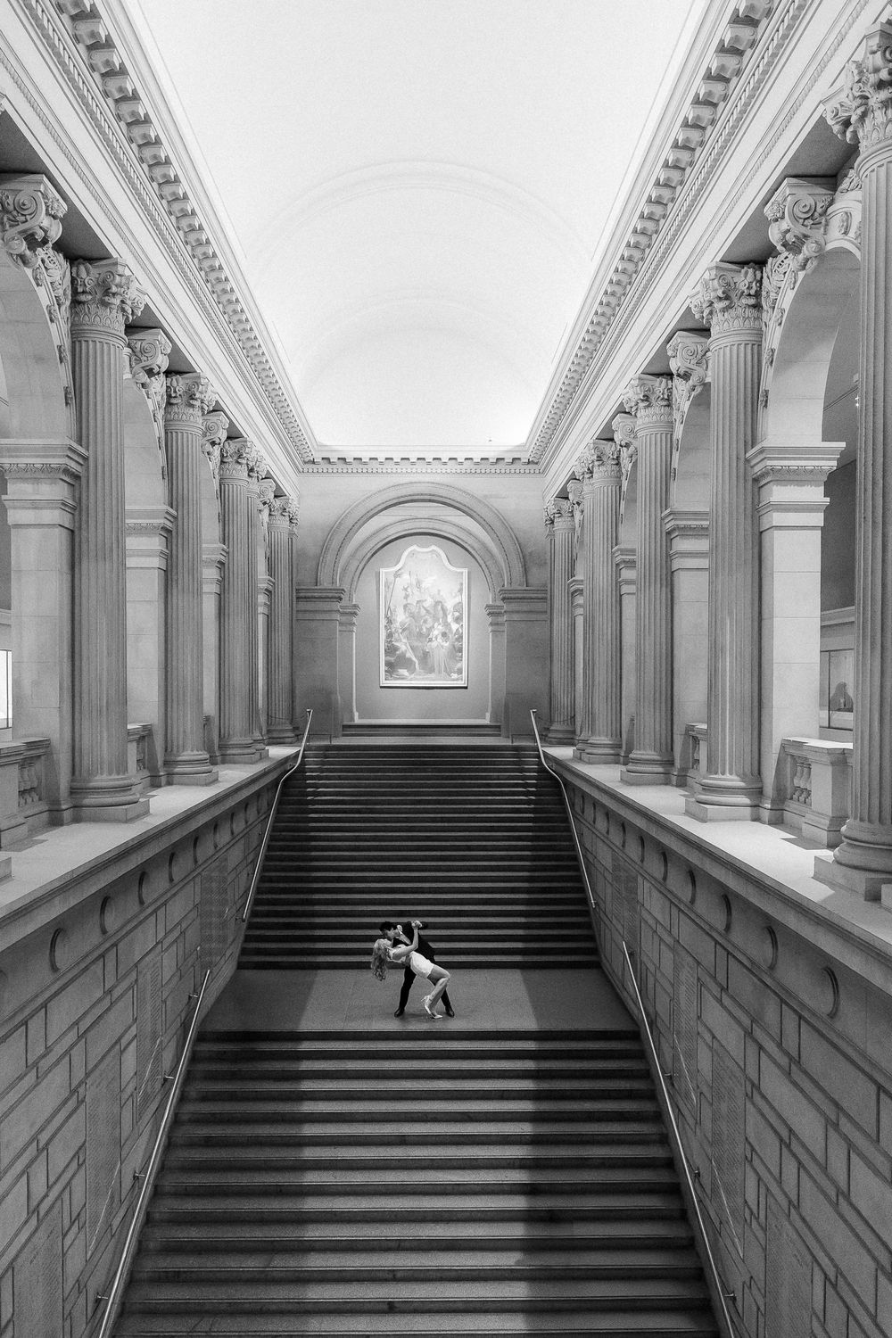 Dramatic black and white view of grand marble staircase with classical columns in ornate historic building.