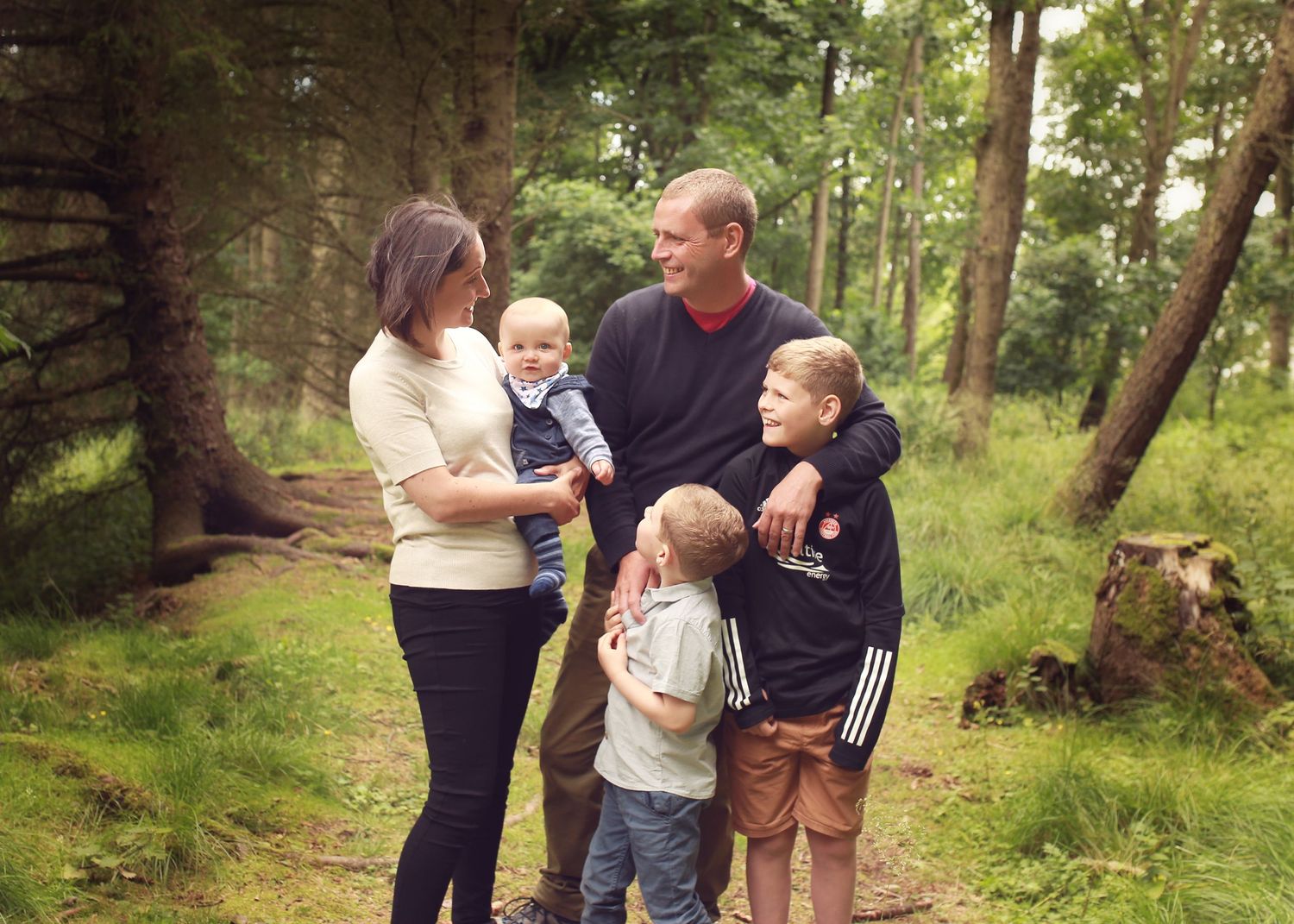 A joyful family enjoying a moment together in the tranquil surroundings of Dunnottar Woods, capturing the beauty of nature and connection