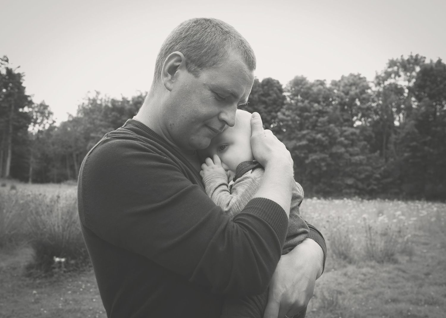 A tender moment between a father and his newborn baby, capturing the bond and love in a serene outdoor setting