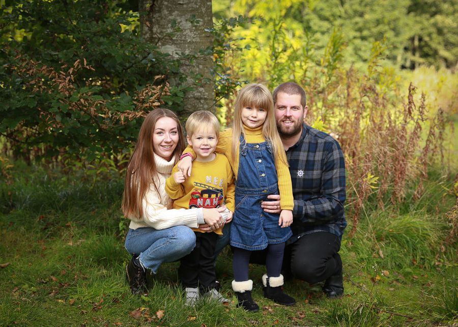 A joyful family enjoying a moment together in the tranquil surroundings of Dunnottar Woods, capturing the beauty of nature and connection
