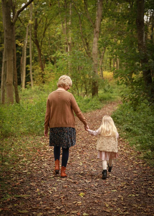 A heartwarming moment between a grandmother and her granddaughter, sharing laughter and connection in the natural beauty of woods