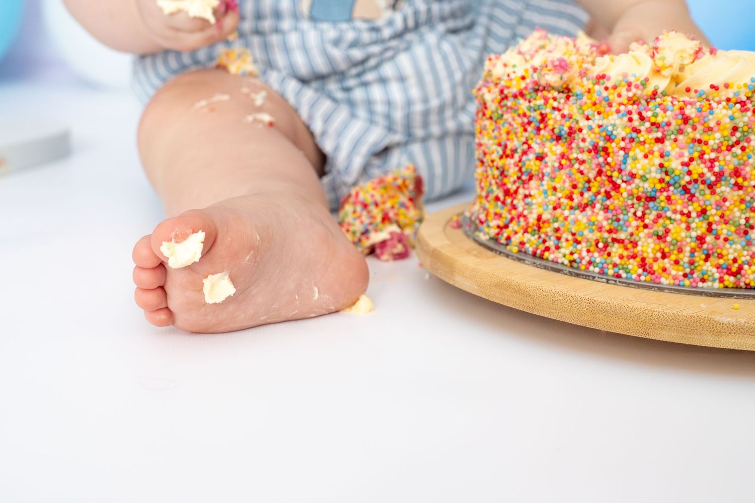 Close-up of sprinkle-covered donut and tiny hands during cake smash photo session.