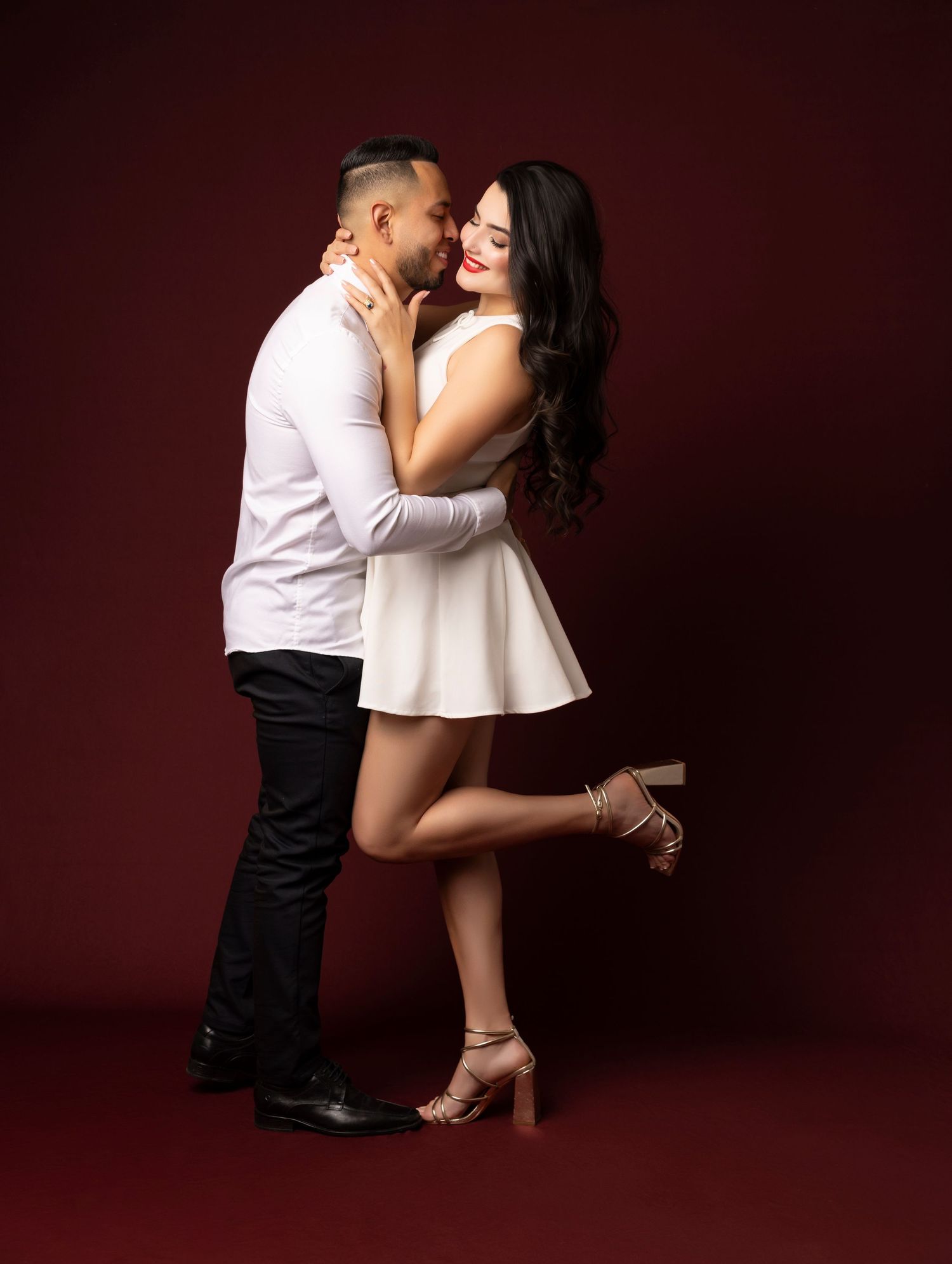 Romantic couple portrait session against burgundy backdrop in studio setting.